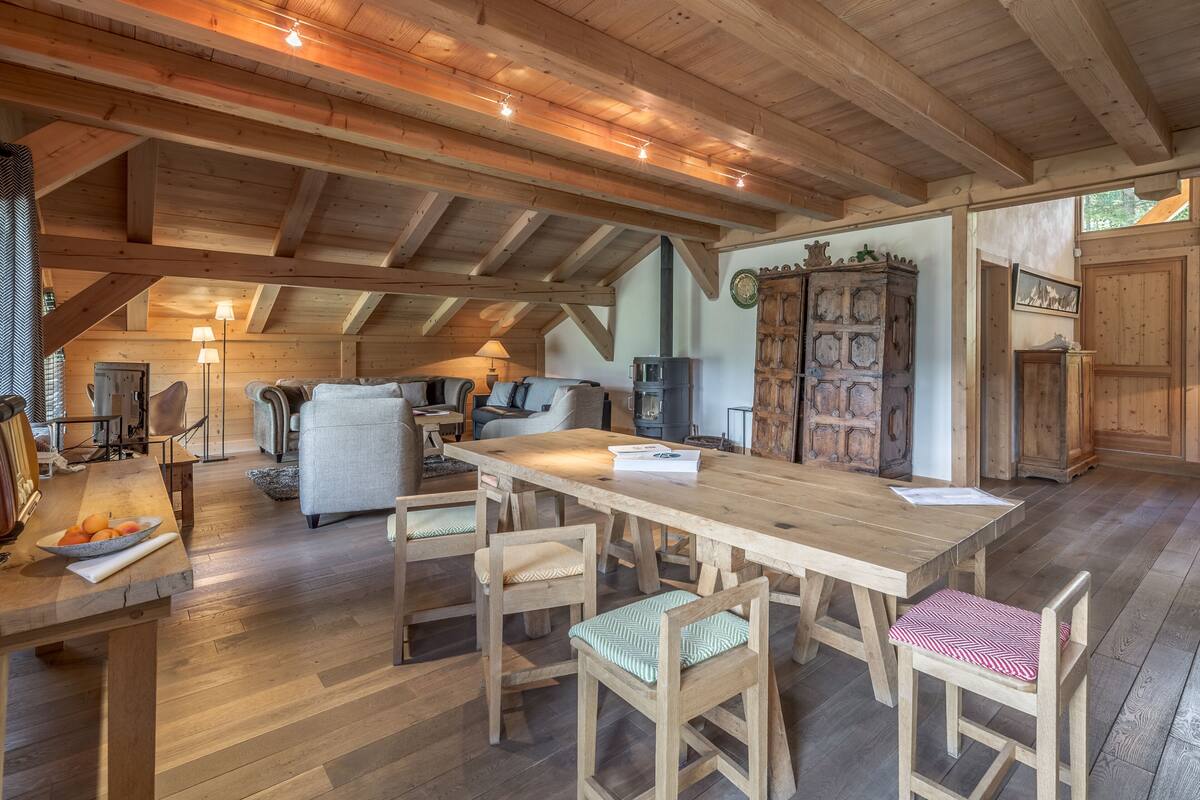 Amplio espacio tipo loft con techo alto, vigas de madera, una gran mesa de comedor y una zona de estar acogedora.