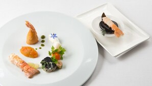 A white plate with various seafood dishes, including a shrimp, salmon, and a black fish. - Hotel de la Marne (Paimpol)