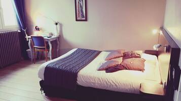 A bedroom with a bed, a desk, and a chair.