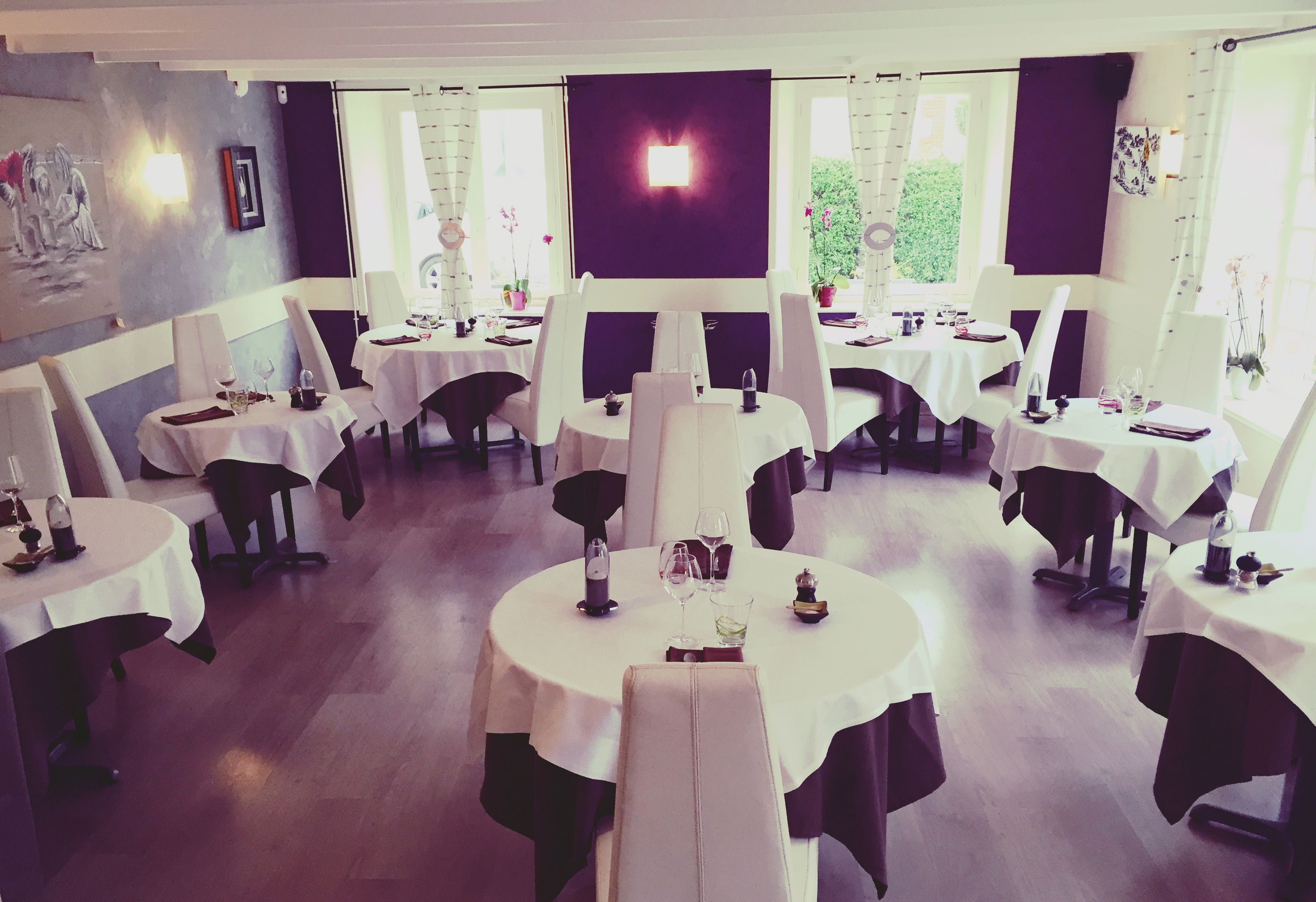 En restaurant med runde borde, hvide duge og sorte stole.