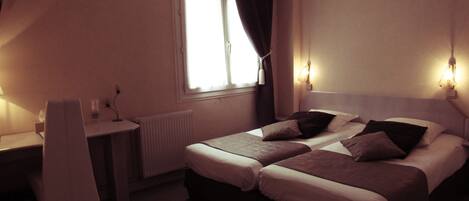 A hotel room with two beds, a desk, and a chair.