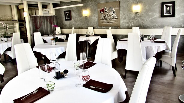 A restaurant with round tables, white tablecloths, and white chairs. - Hotel de la Marne (Paimpol)