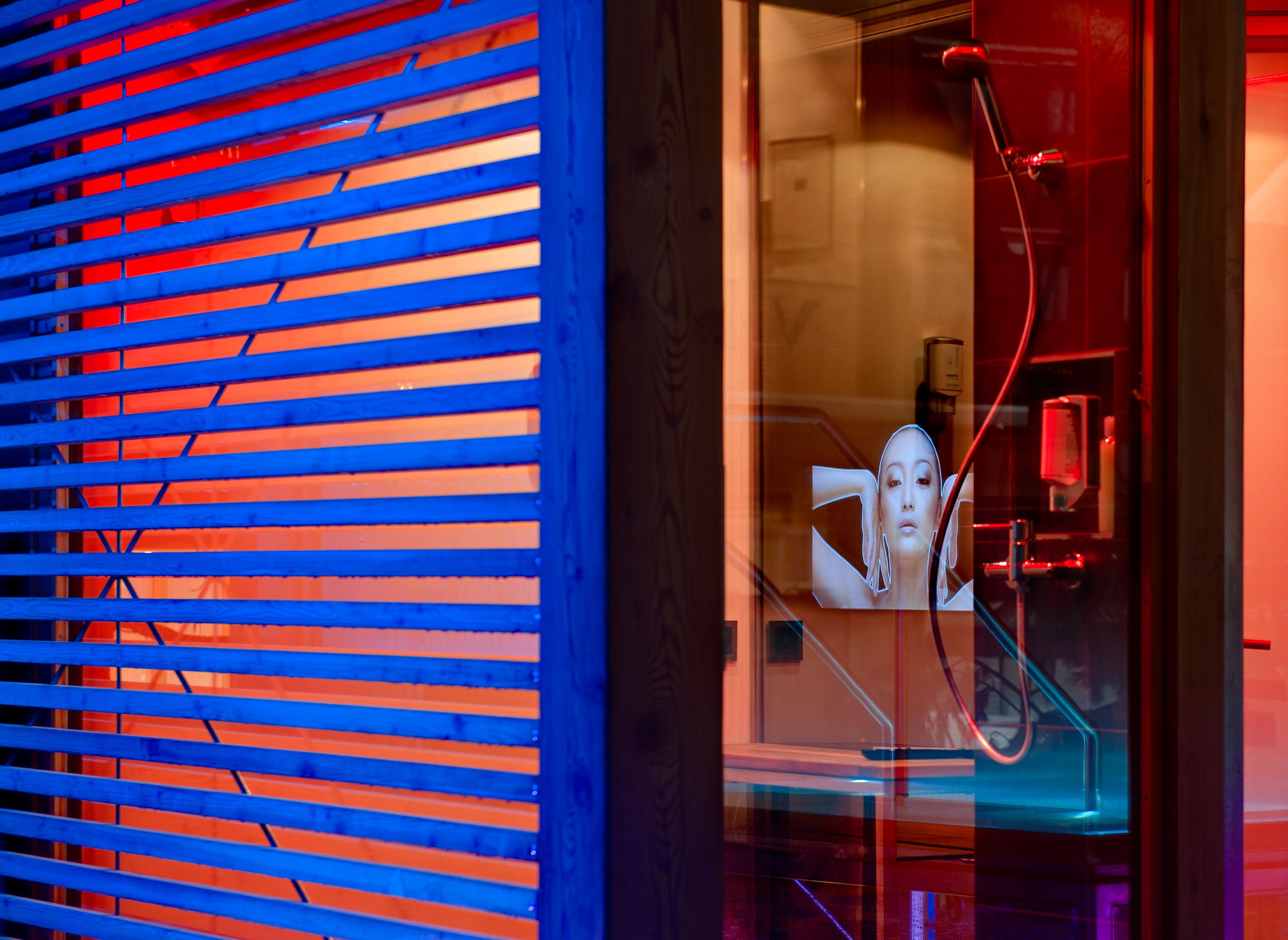 Un intérieur moderne avec des stores horizontaux, une porte vitrée et des éléments de plomberie apparents.