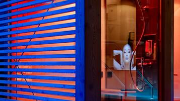 Un intérieur moderne avec des stores horizontaux, une porte vitrée et des éléments de plomberie apparents.