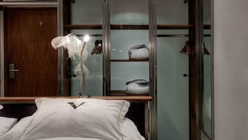 A bedroom with a bed, a nightstand, a mirror, and a wardrobe with shelves.