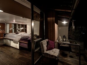 Quarto moderno com cama grande, banheiro com paredes de vidro e varanda com vista para a cidade.