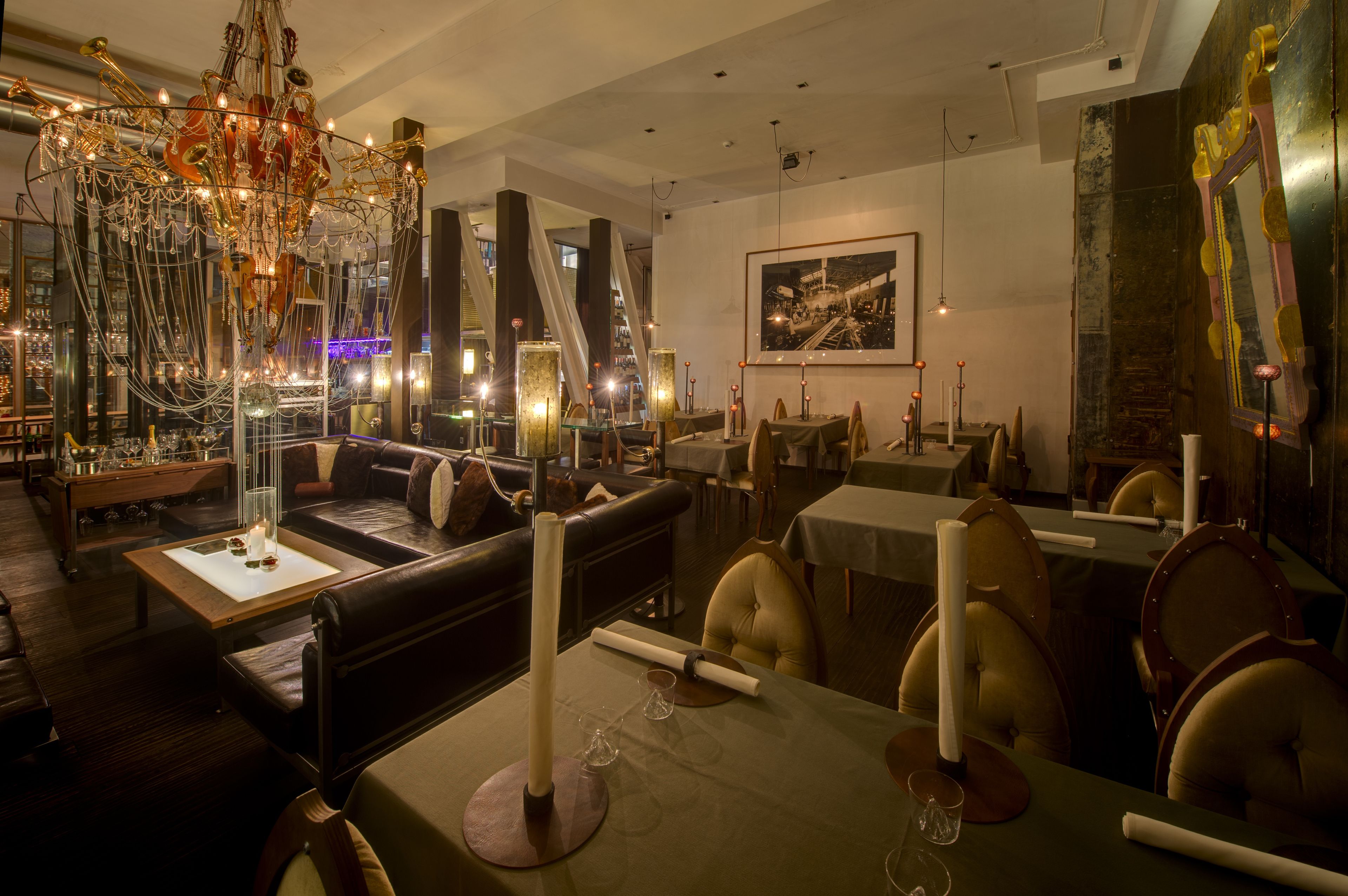 A modern dining area with leather seating, a chandelier, and a large framed picture on the wall.