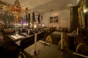 Uma sala de jantar moderna com assentos de couro, um candelabro e um quadro grande na parede.