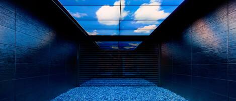A modern interior with a skylight ceiling, a patterned floor, and dark walls.