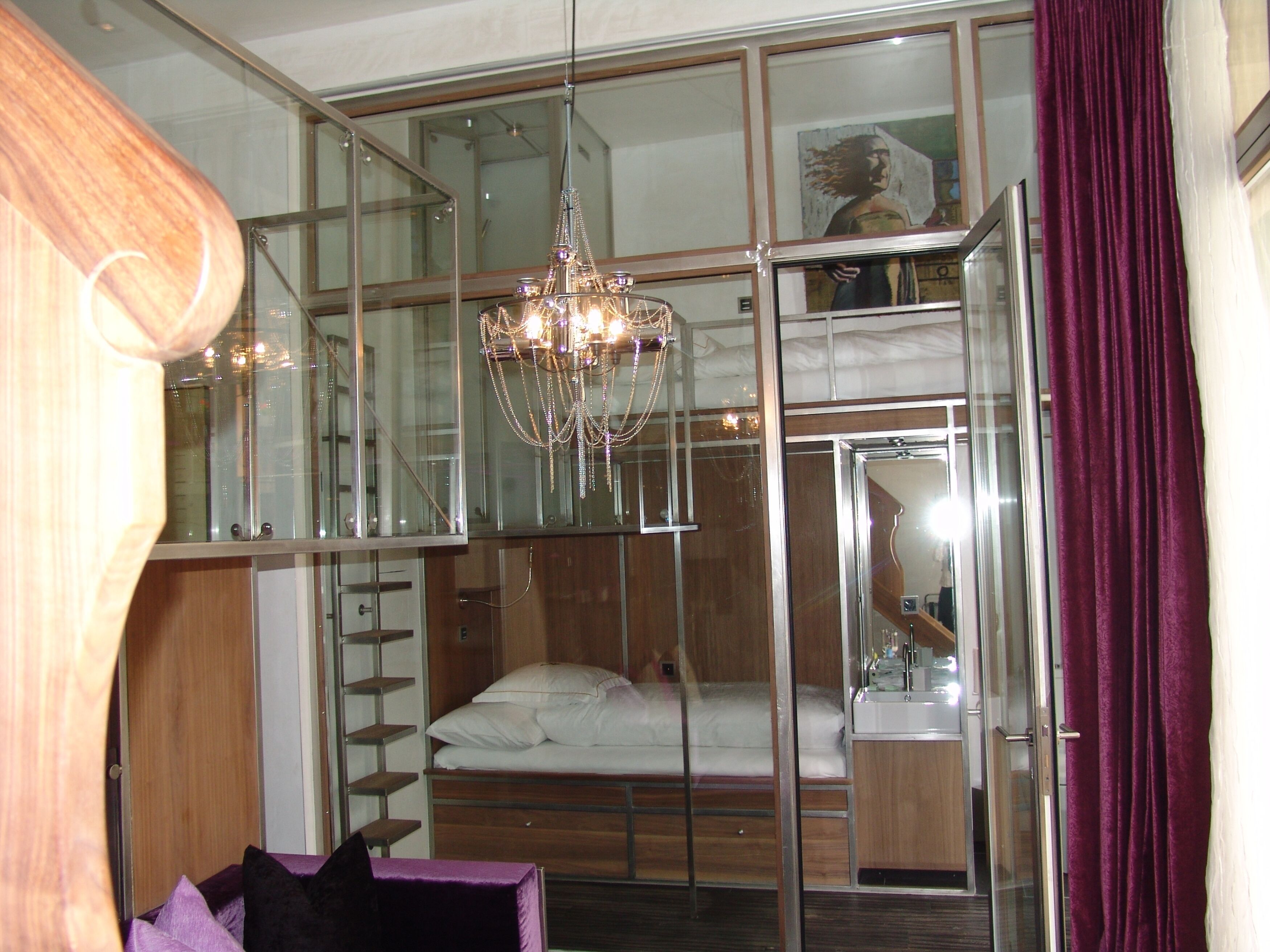 A modern room with a bunk bed, a chandelier, and a glass partition.