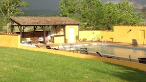 Ein Poolbereich mit einem Pavillon, einem kleinen Pool und einer Rasenfläche.