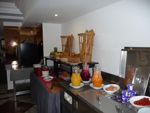 A buffet setup with various food items and beverages. - Hotel Kamal (Agadir)