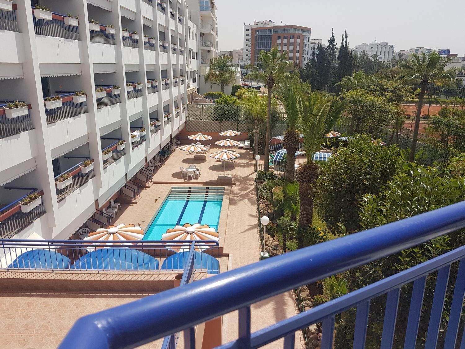 Un hotel con piscina, mobiliario exterior y vistas a la ciudad.