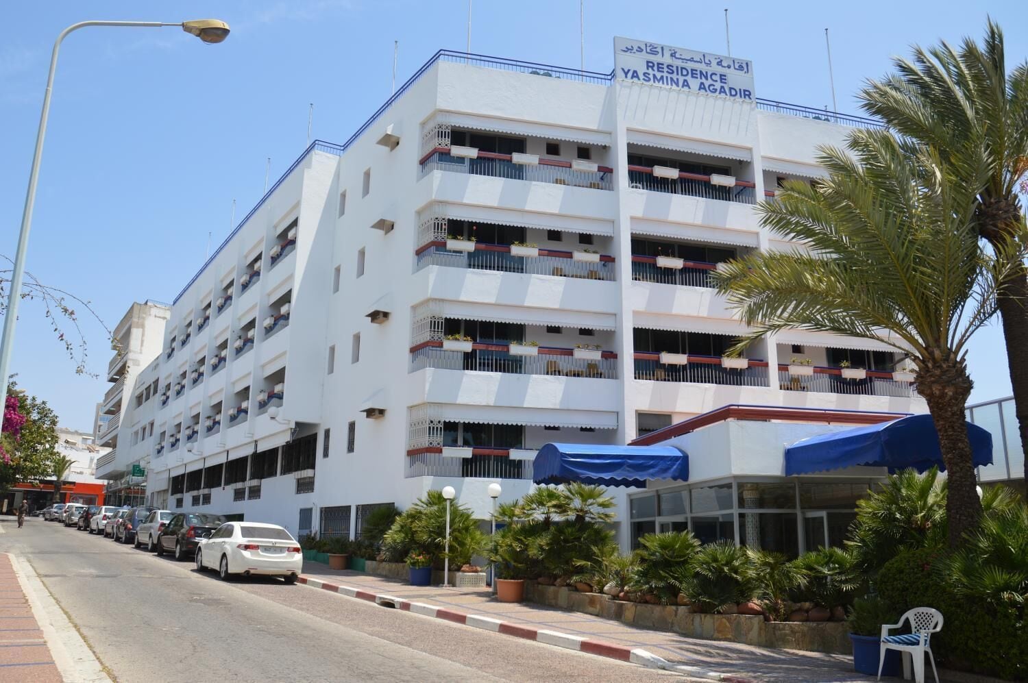 A multi-story building with balconies, a covered entrance, and a sign indicating it is a residence named Yasmina Agadir.