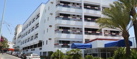 A multi-story building with balconies, a covered entrance, and a sign indicating it is a residence named Yasmina Agadir.