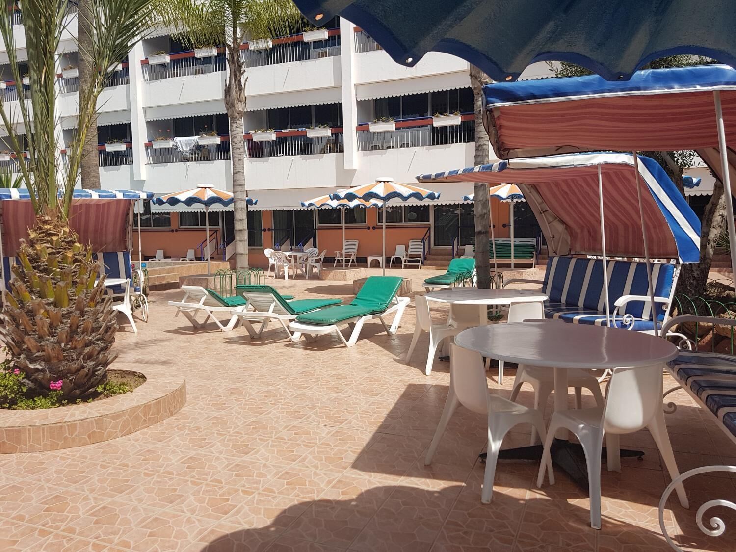 Eine Außenpatio-Terrasse mit Lounge-Möbeln, Tischen und Sonnenschirmen.