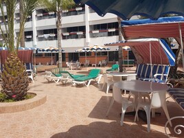 Eine Außenpatio-Terrasse mit Lounge-Möbeln, Tischen und Sonnenschirmen.