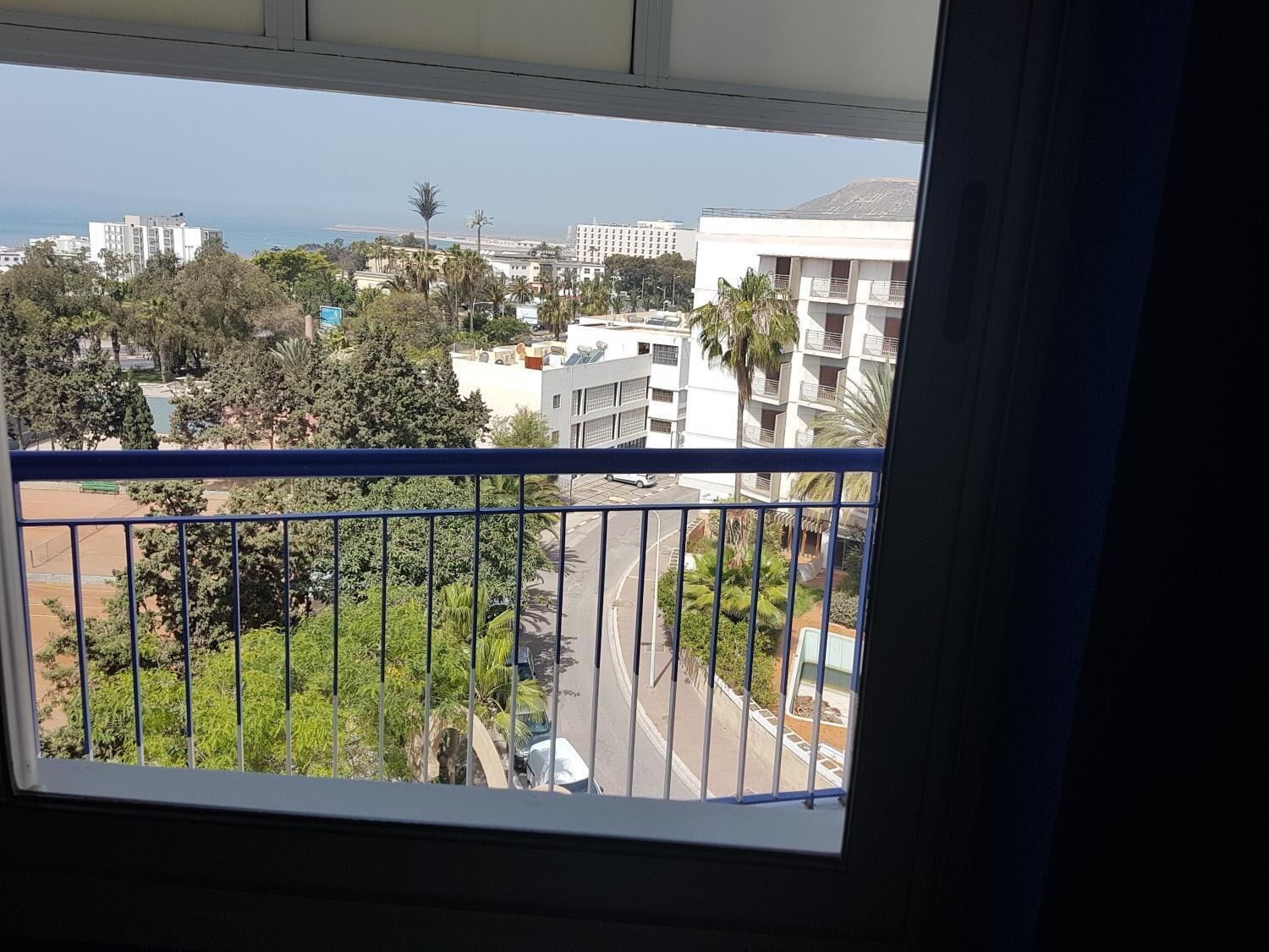 A balcony with a view of a cityscape, including buildings and a body of water.