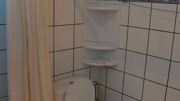 A bathroom with a toilet, a water tank, and a shower curtain.