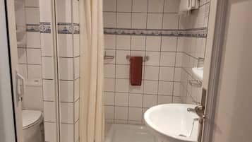 Een badkamer met een douche, toilet en wastafel.