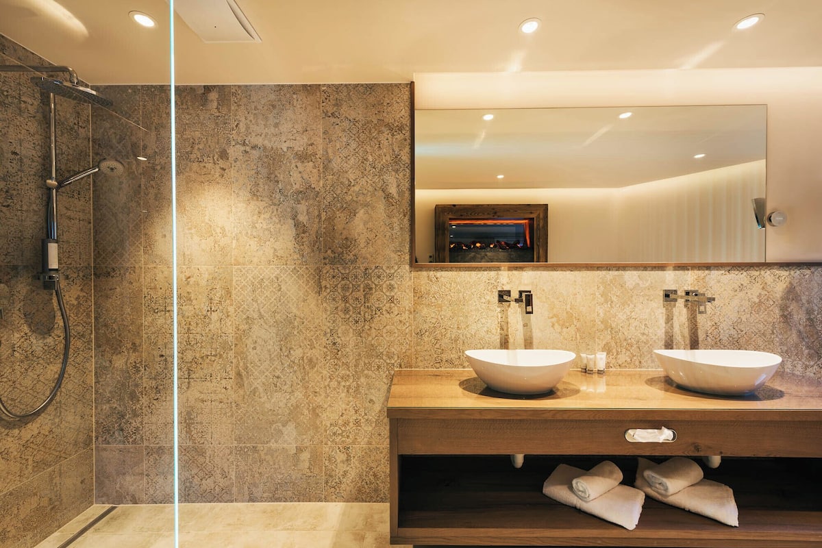 A bathroom with two sinks, a shower, and a mirror.