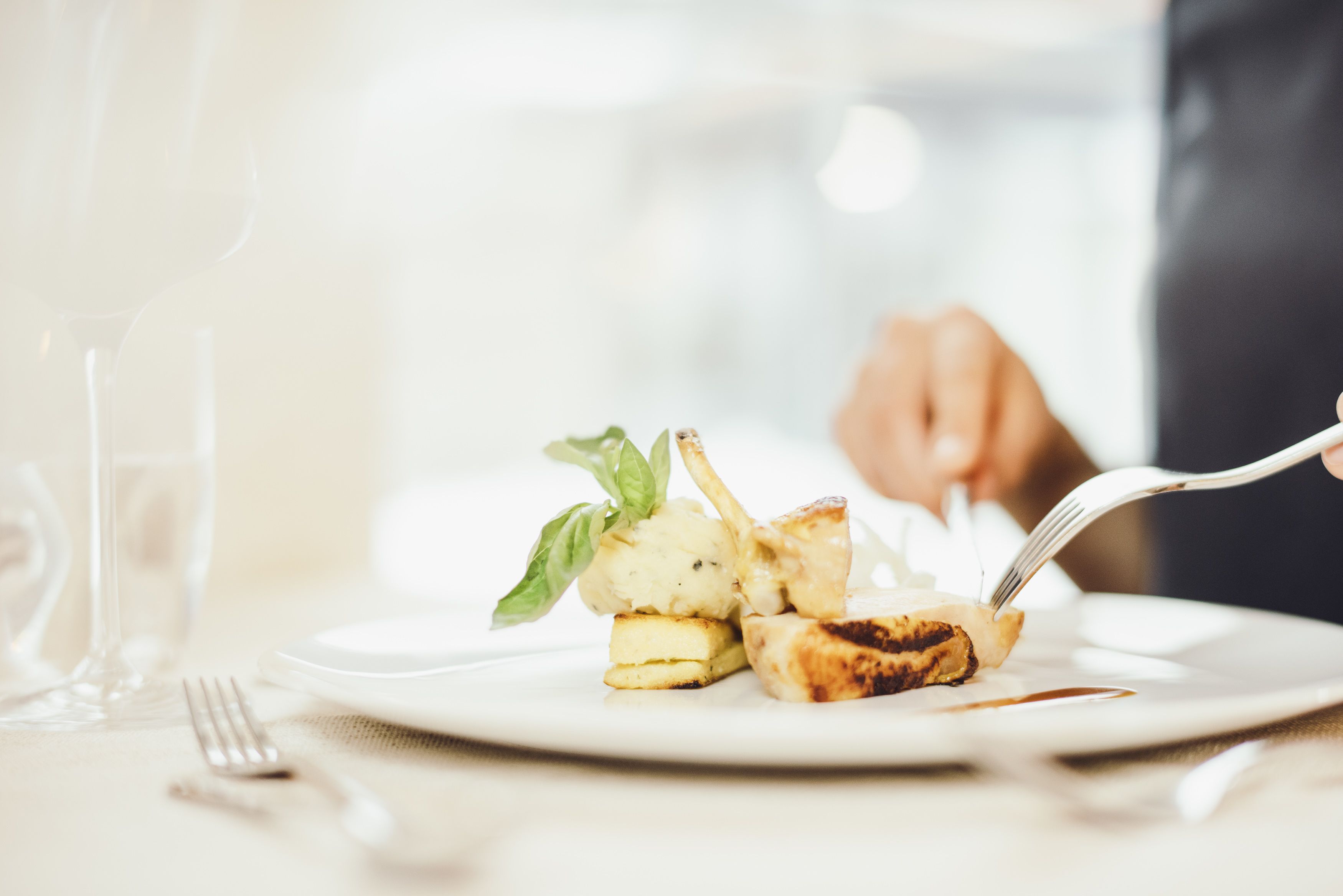 A plate with a grilled item, possibly chicken, and a piece of bread, with a fork on the side.