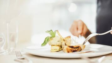 A plate with a grilled item, possibly chicken, and a piece of bread, with a fork on the side.