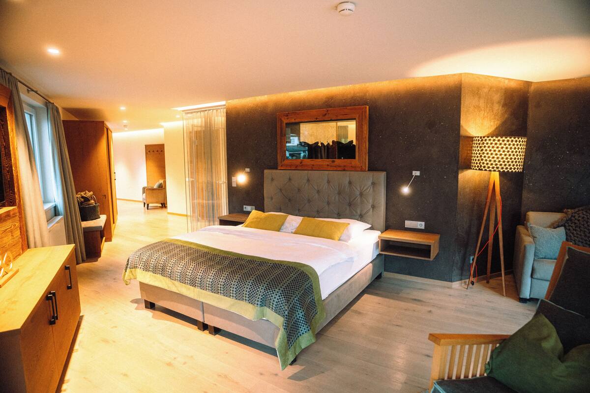 Un dormitorio moderno con una cama grande, mesitas de noche, un espejo y una lámpara de pie.