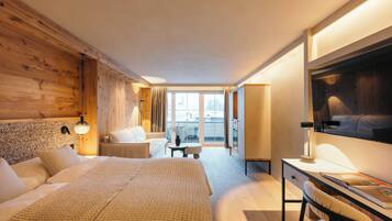 Habitación de hotel con una cama grande, un escritorio, una silla, una mesita y un ventanal con vistas a la ciudad.