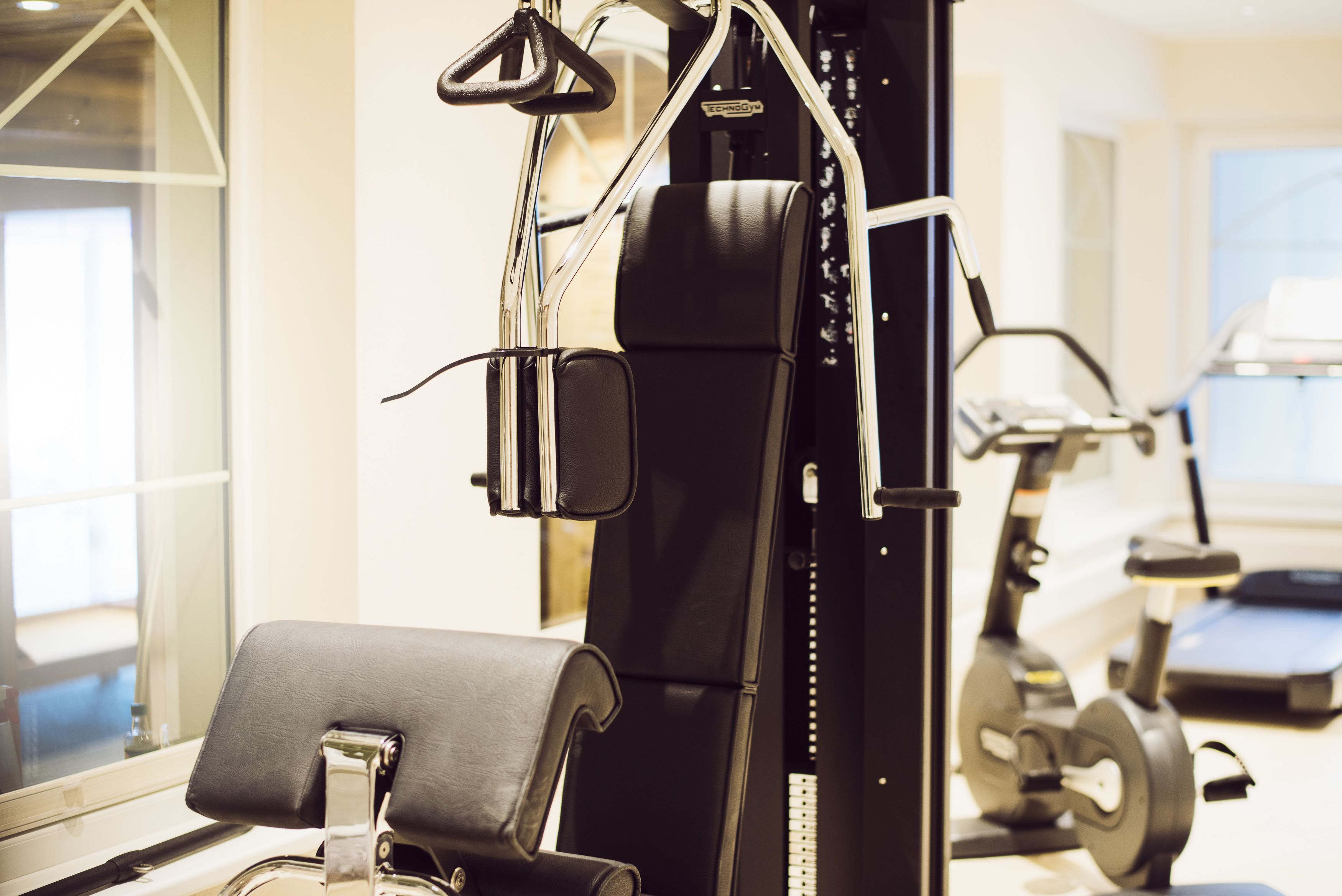 Ein Fitnessstudio mit Trainingsgeräten, darunter ein Kraftgerät und ein Crosstrainer.