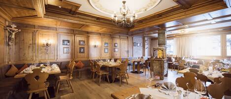Un comedor amplio con paneles de madera, candelabros y varias mesas dispuestas para recibir a los comensales.