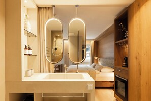 A modern bathroom with a large mirror, a sink, and a shower. - Activehotel Bergkönig (Neustift Im Stubaital)