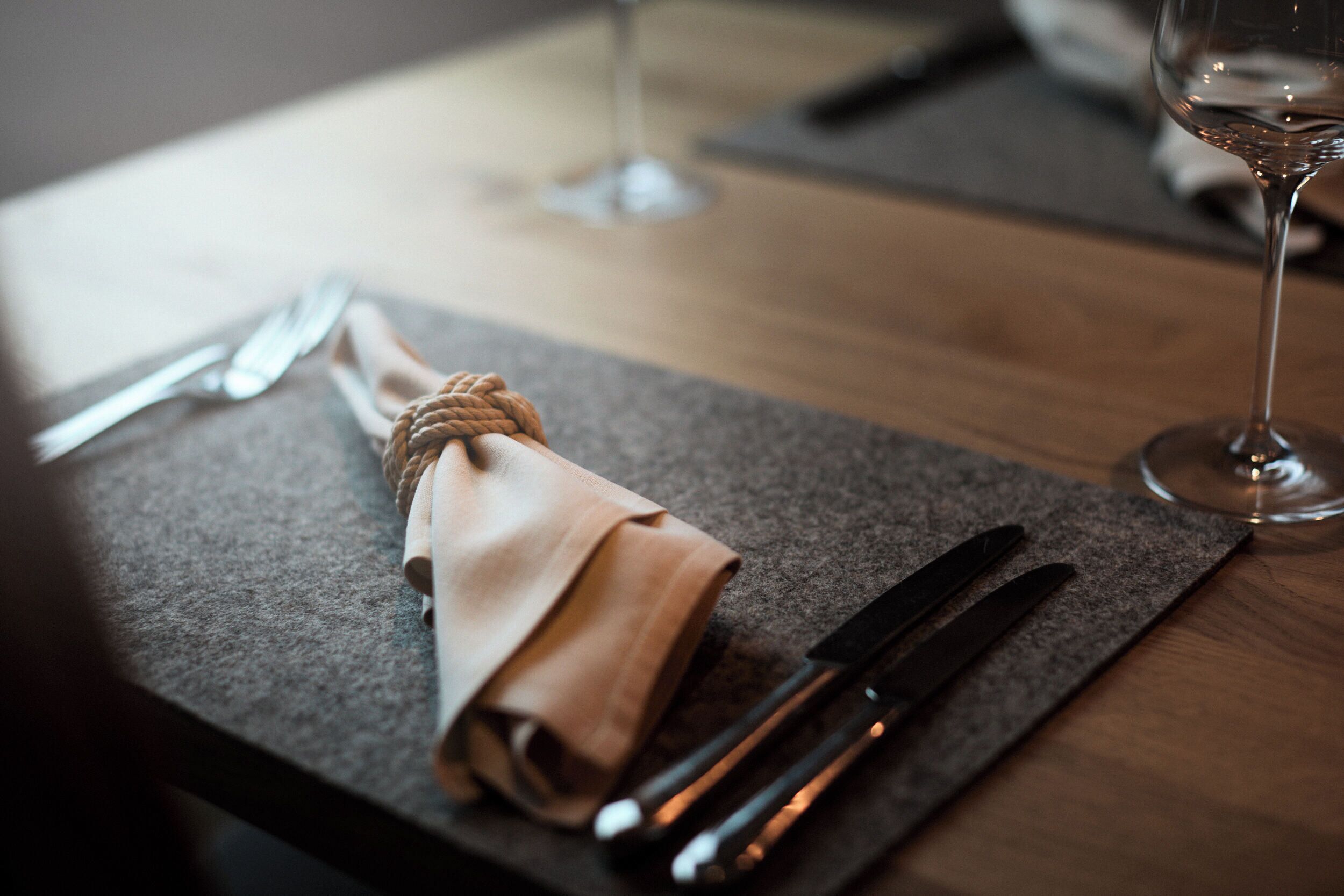 Een gedekte tafel met een gevouwen servet vastgebonden met touw, een mes en een vork.