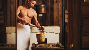 Una persona en una sauna con paredes y banco de madera.