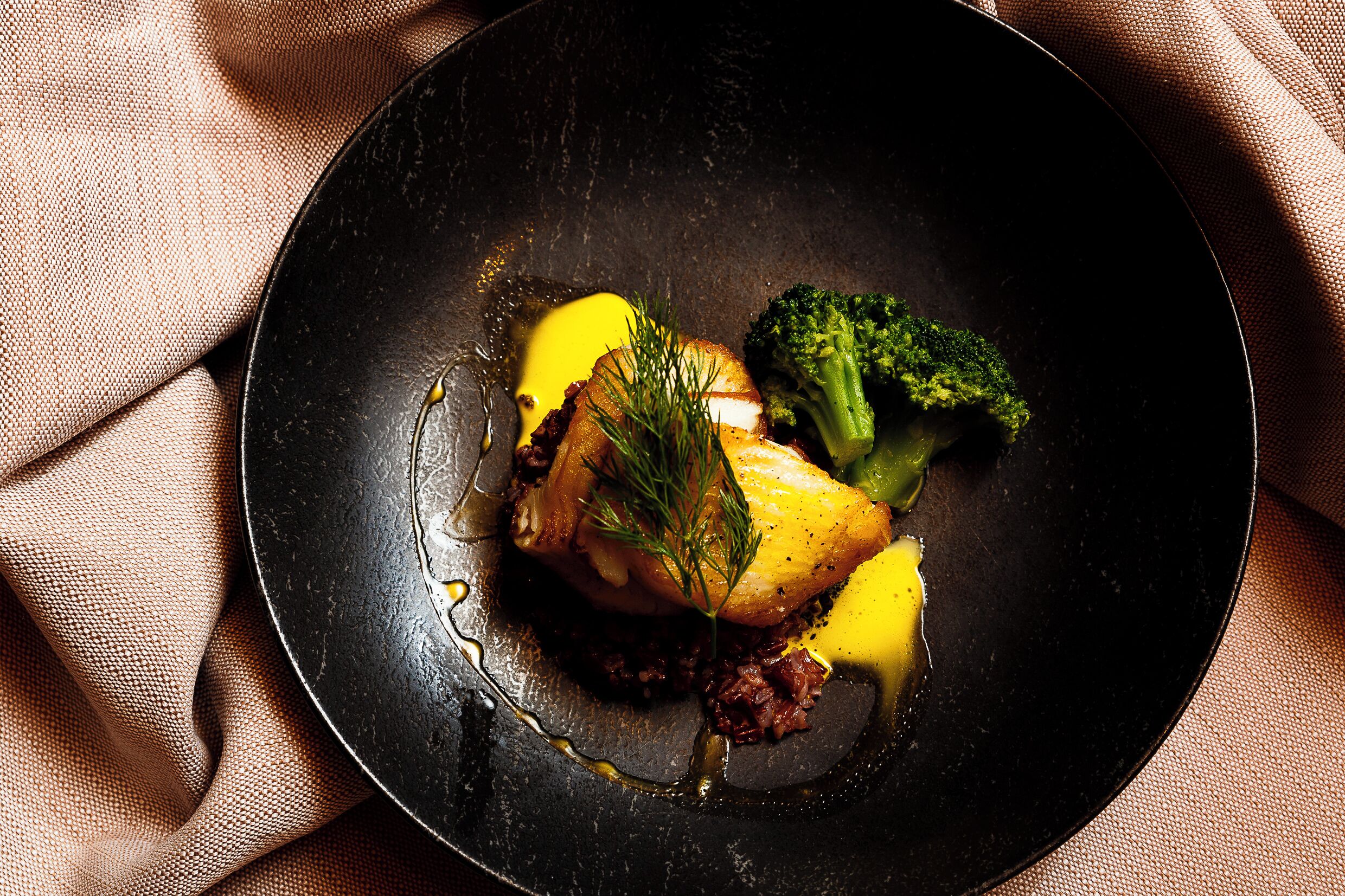A plate with food, including a piece of meat, a vegetable, and a sauce.