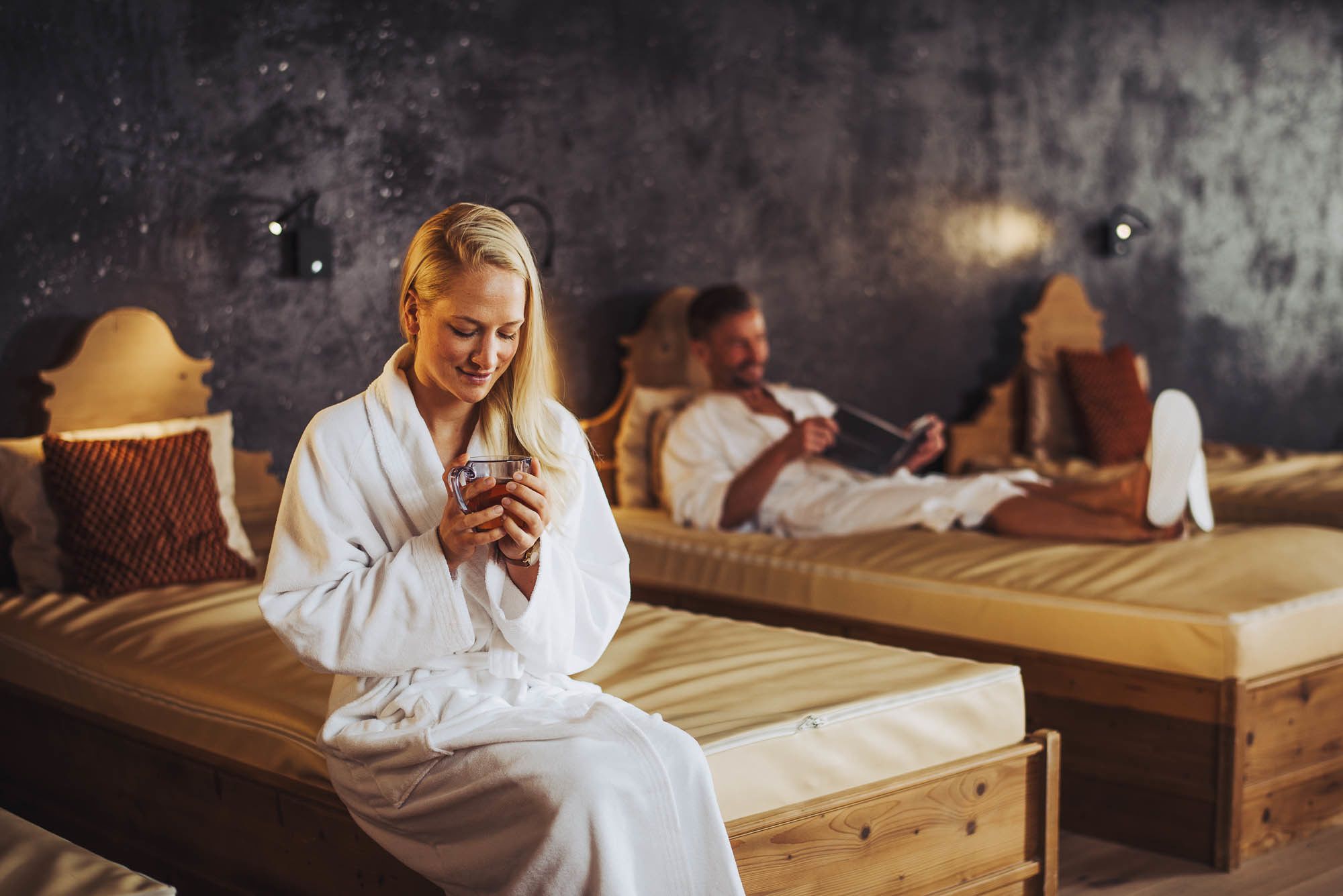 Un cuarto de spa con camas de madera y una pared oscura con textura.