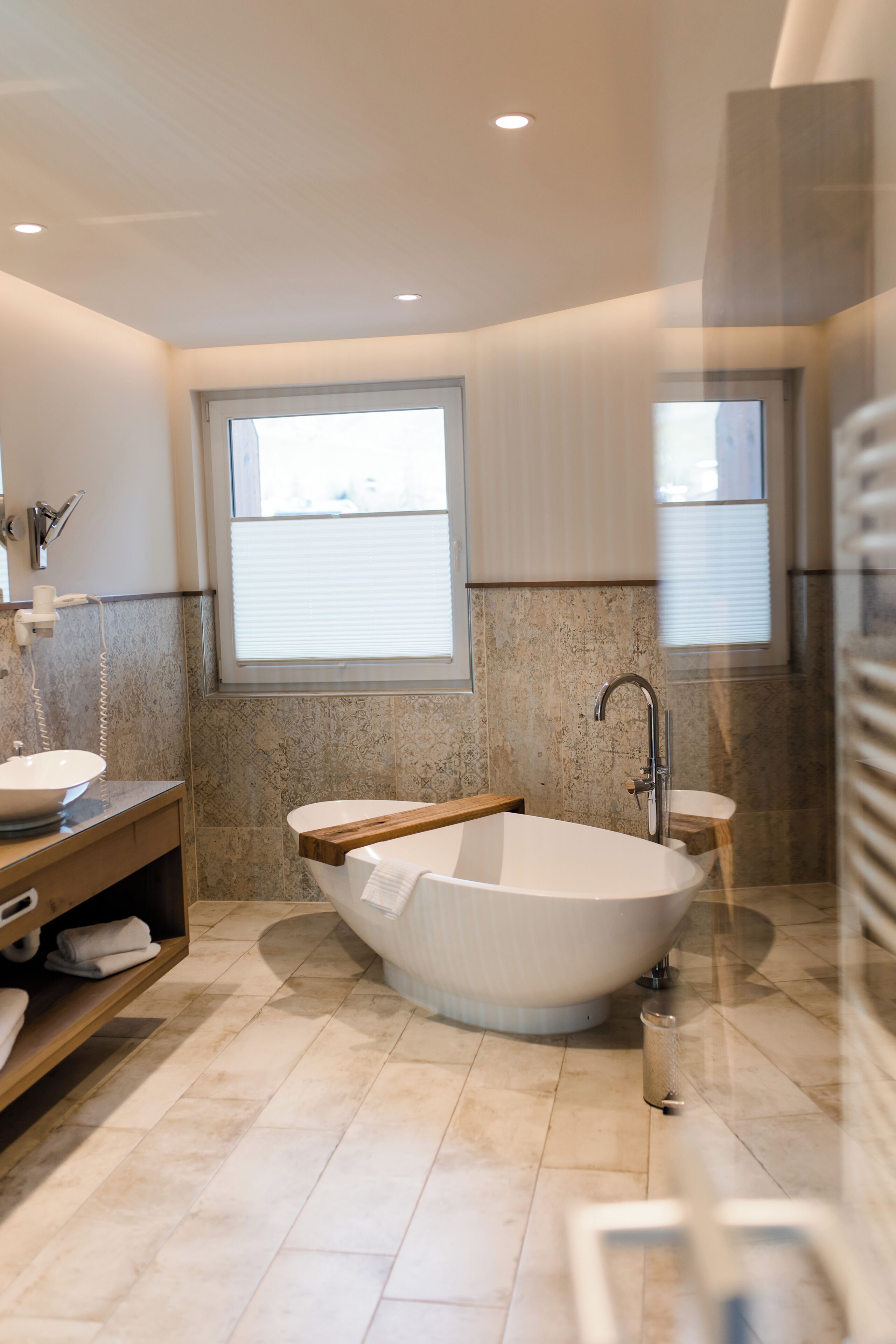 Un baño moderno con una bañera independiente, un tocador con lavamanos y un ventanal que proporciona luz natural.