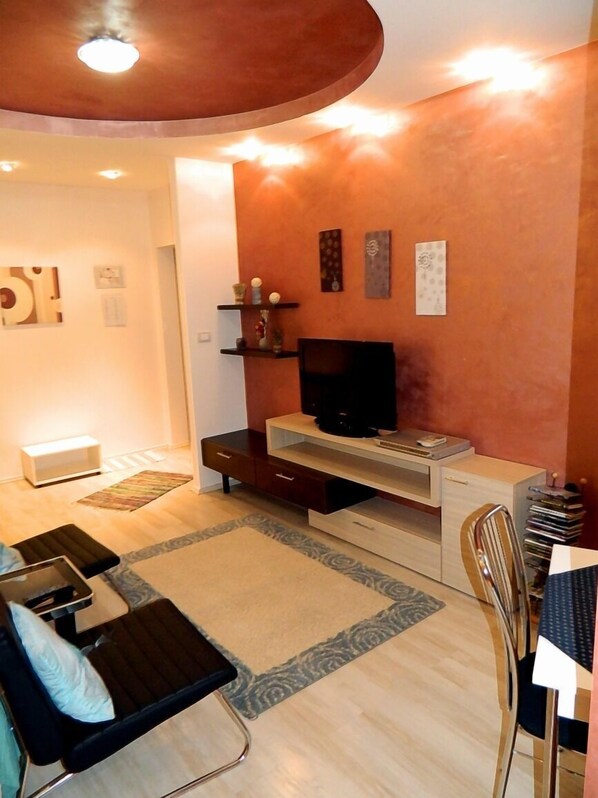 Una sala de estar moderna con una televisión de pantalla plana, un sofá, una mesa de comedor y una mesa de centro.
