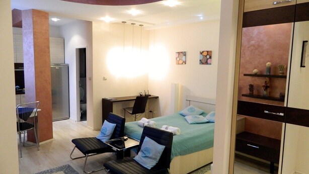 A modern hotel room with a bed, two chairs, a desk, and a mirror. - Apartment Vivo (Belgrade)