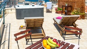 A rooftop terrace with wooden furniture, a hot tub, and a table with fruit. - Boutique Hotel Fortino (Chania)