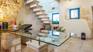 A modern interior with a glass desk, a stone wall, a wooden staircase, and a small window. - Boutique Hotel Fortino (Chania)