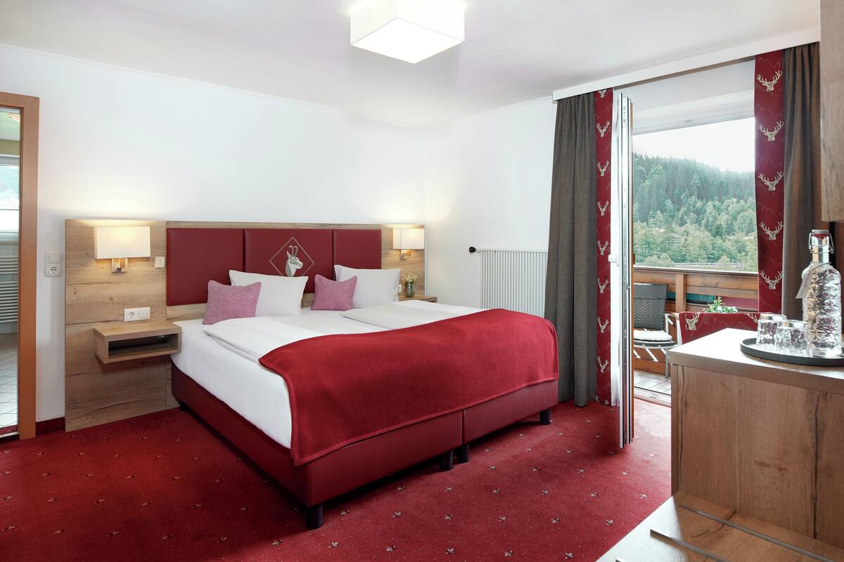 Een hotelkamer met een bed, nachtkastjes, een dressoir en uitzicht op het landschap.