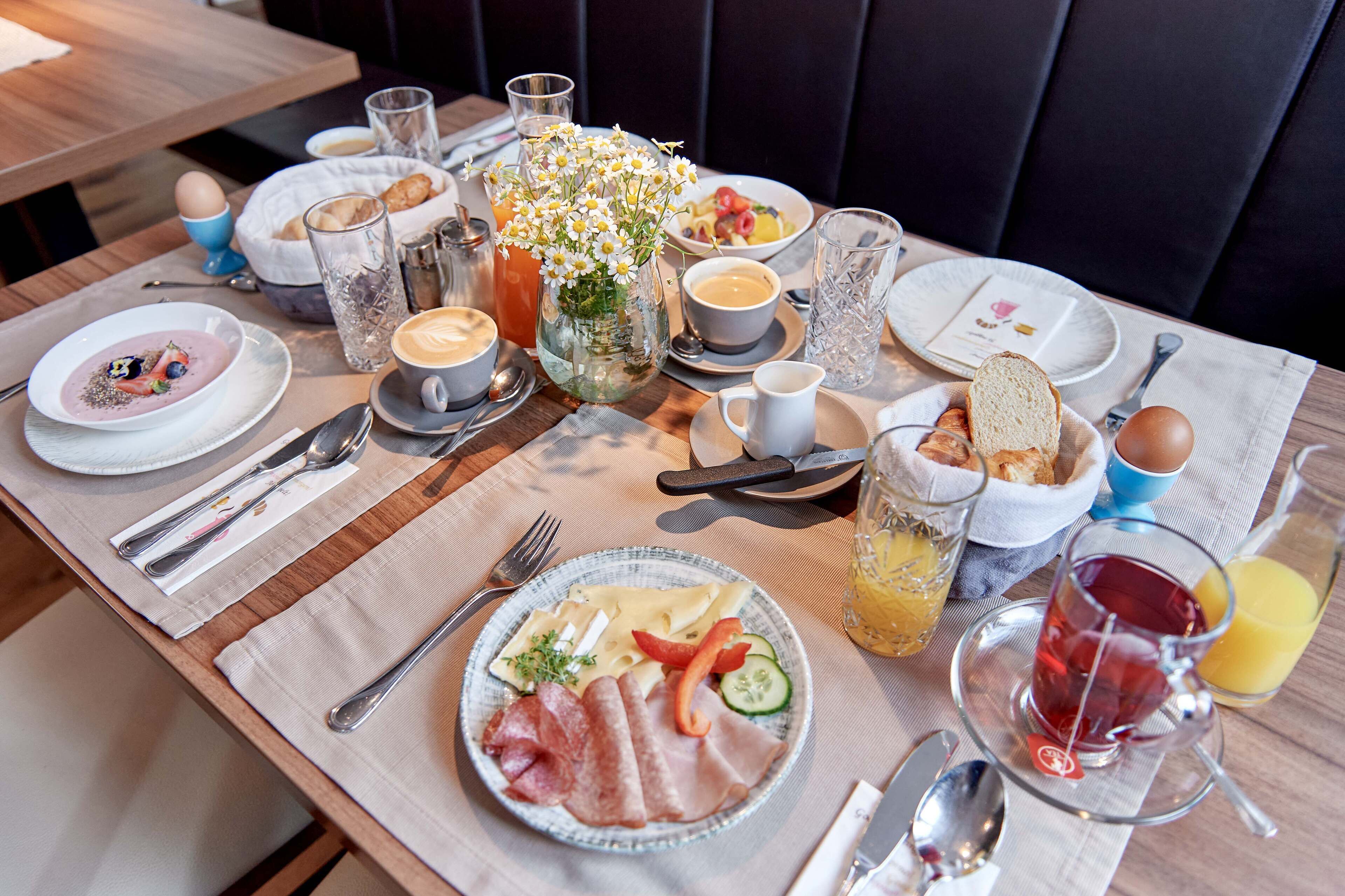 A breakfast setting with various dishes, drinks, and utensils on a table.