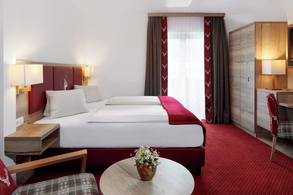 Hotelkamer met een bed, nachtkastjes, een bureau, een stoel en een kleintje tafeltje met een vaas.
