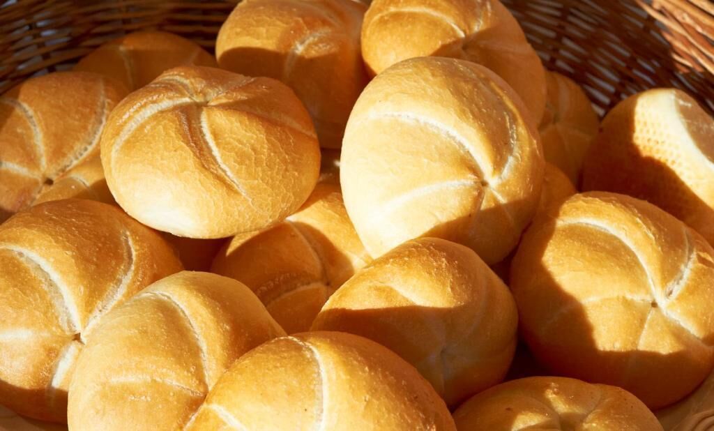 A basket filled with round, golden-brown bread rolls.