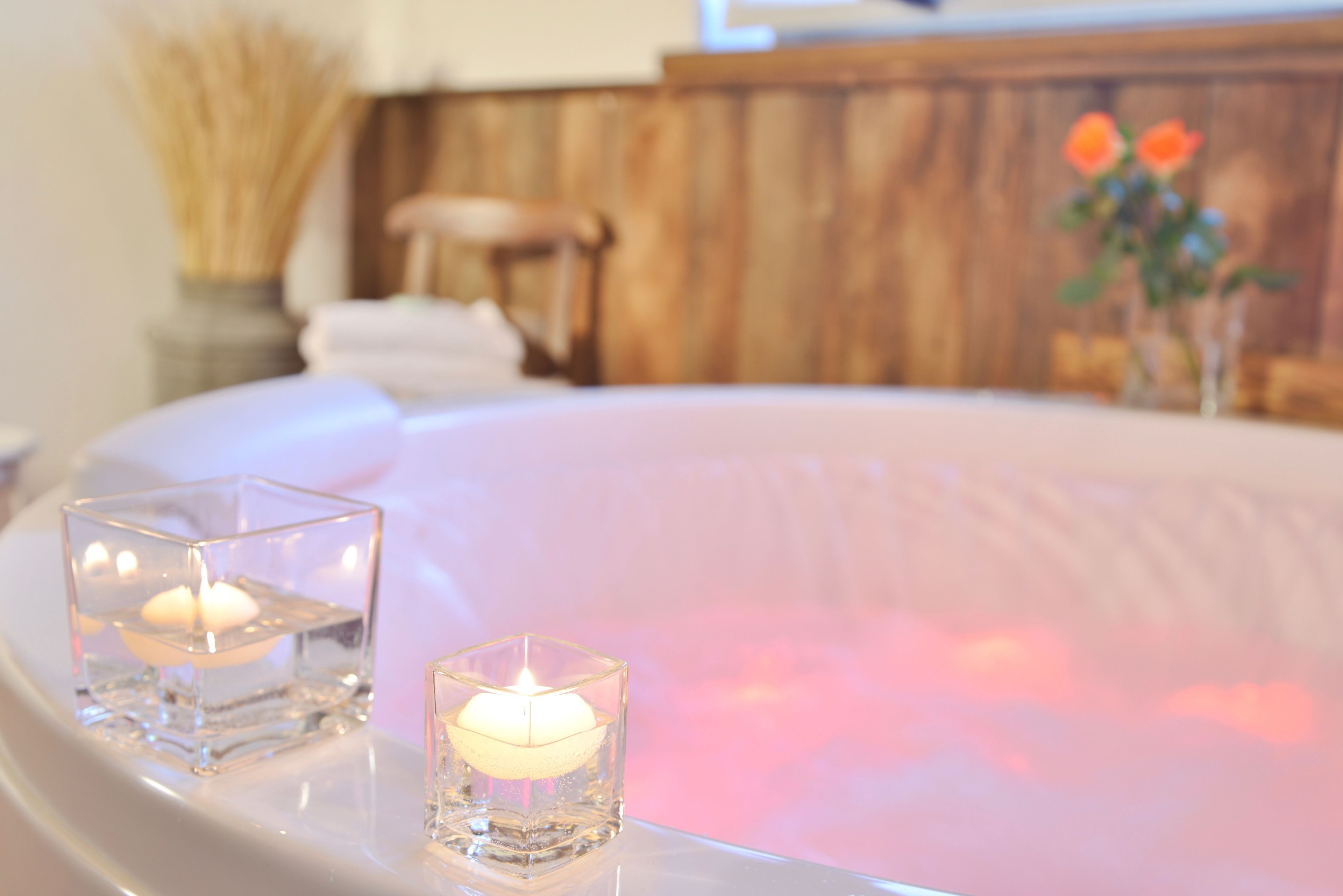 A spa tub with two lit candles in glass holders.