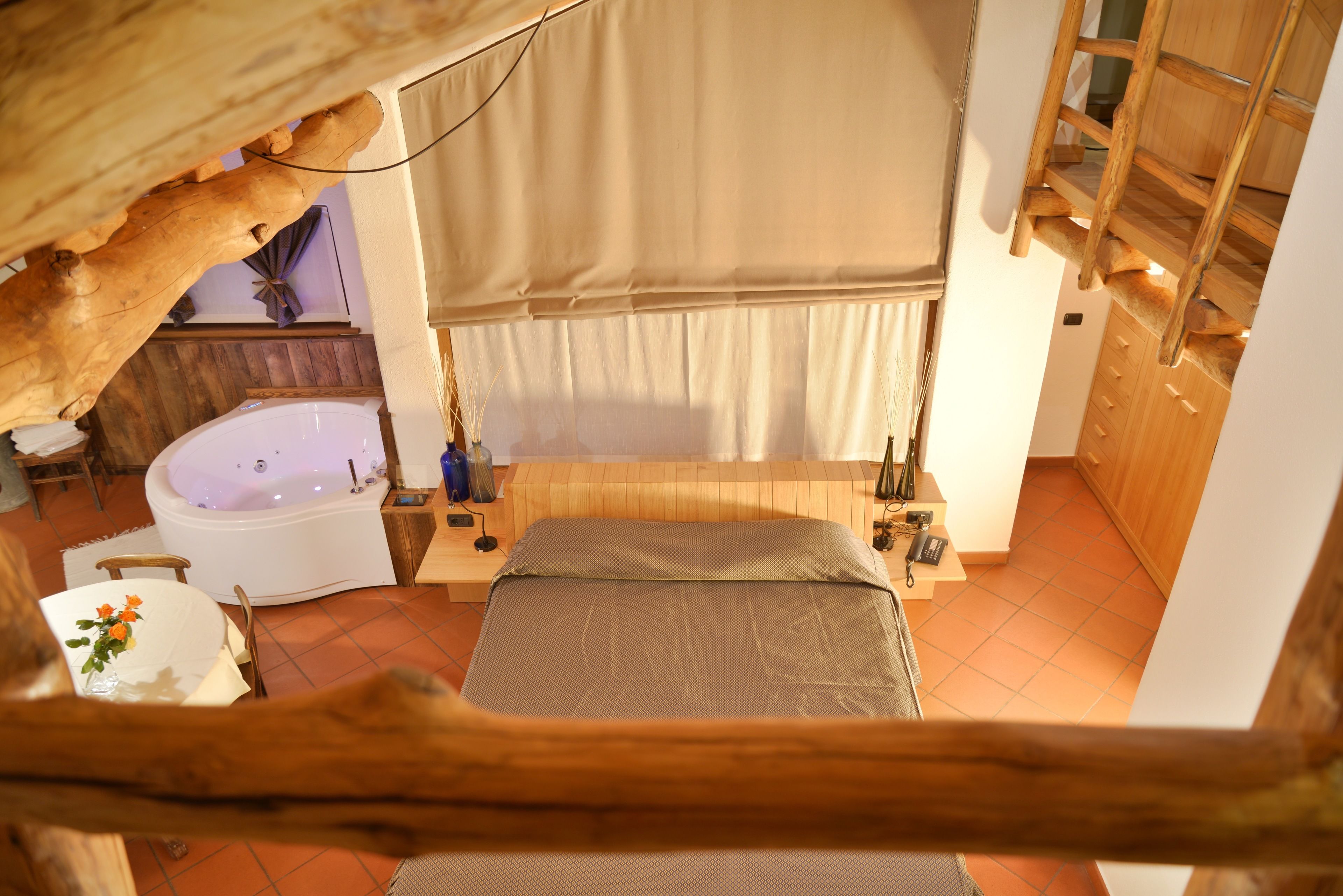 Un dormitorio con una cama grande, un baño independiente con bañera y un techo de estructura de madera.