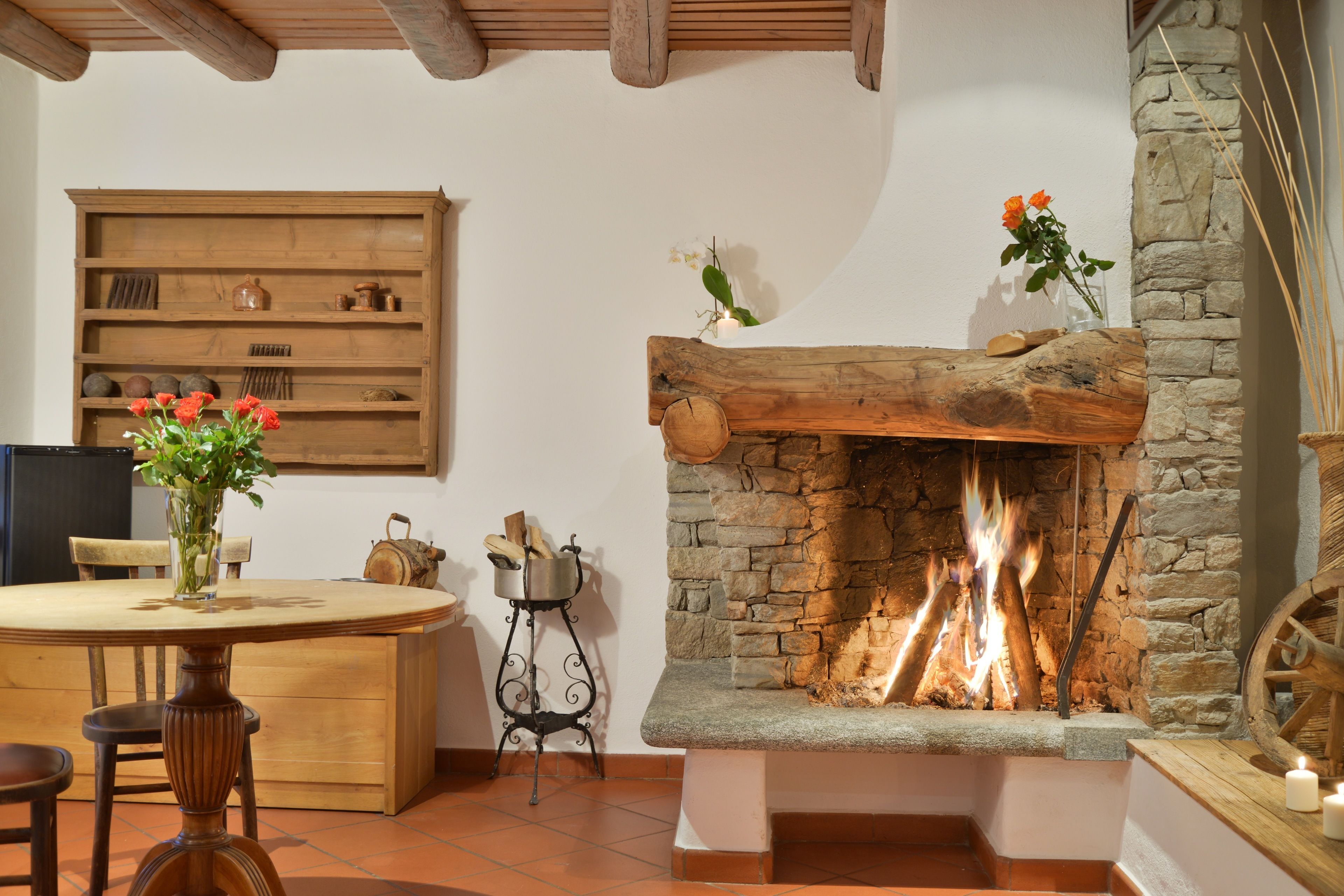Un interior rústico con chimenea de piedra, muebles de madera y una estantería.