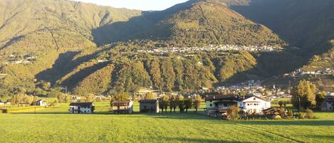 A rural landscape with a village nestled in the valley, surrounded by mountains.