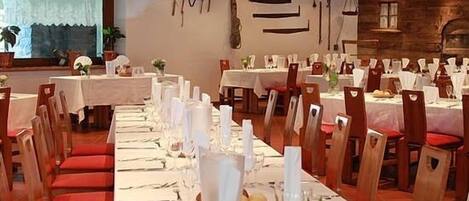 A restaurant with multiple tables set for dining, wooden chairs, and a rustic interior.